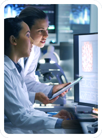 Two lab technicians reviewing cell images on a computer monitor for a biomarker analysis project.